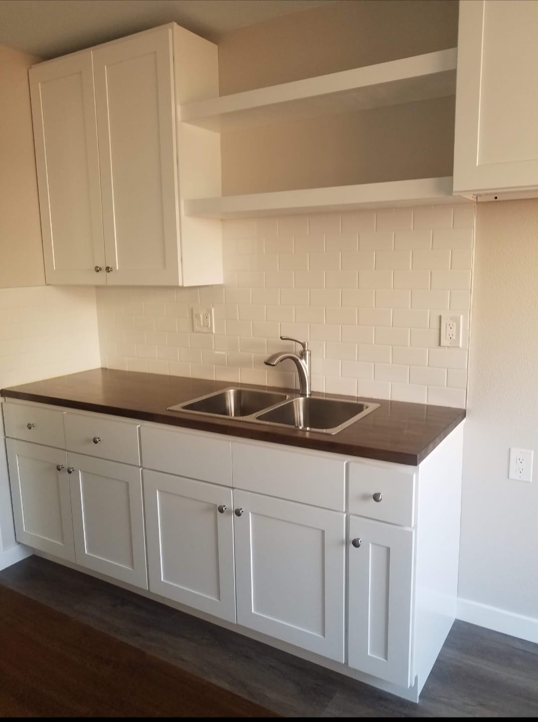 Kitchen after — new white shaker cabinets with dark countertop and subway tile