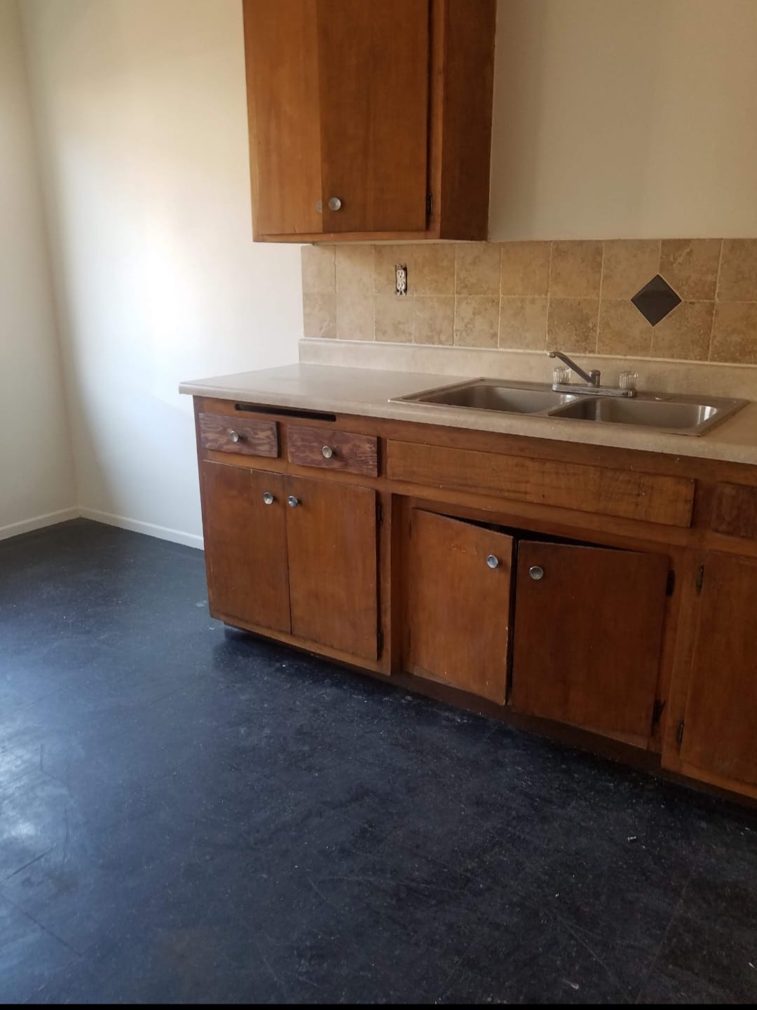 Kitchen before — original wooden cabinetry with beige tile backsplash