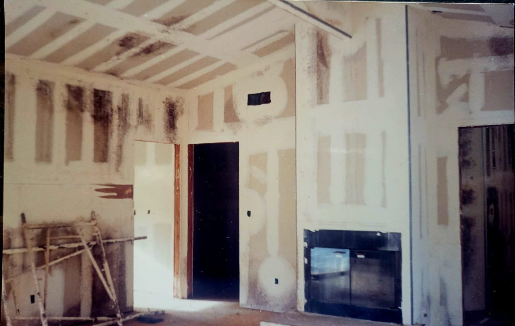 Interior before — unfinished room with exposed ceiling beams and drywall